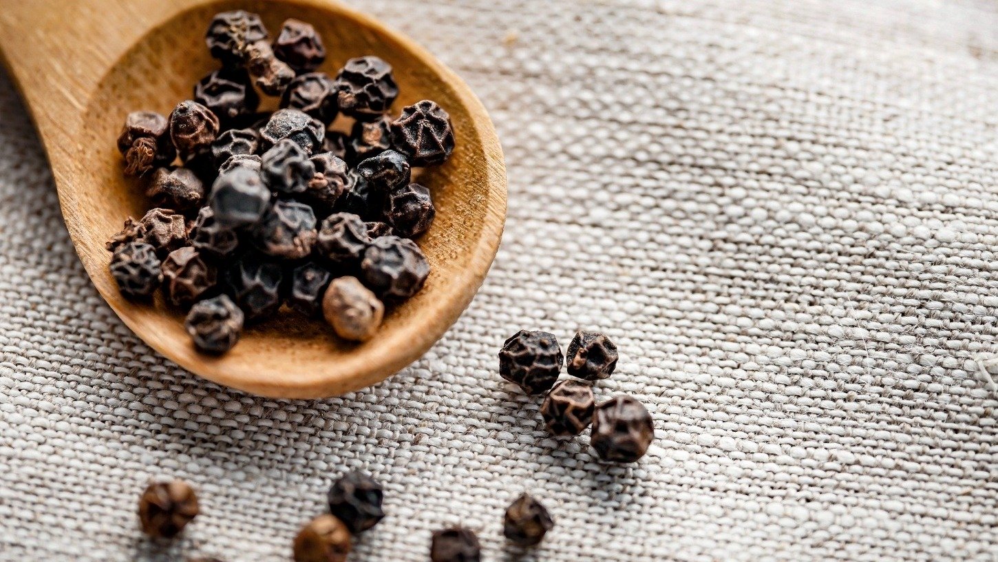 black pepper corns on a wooden spoon